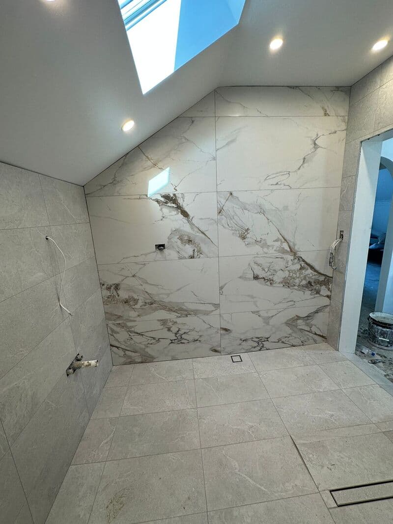 Large marble-look wall tiles in a bathroom with a skylight