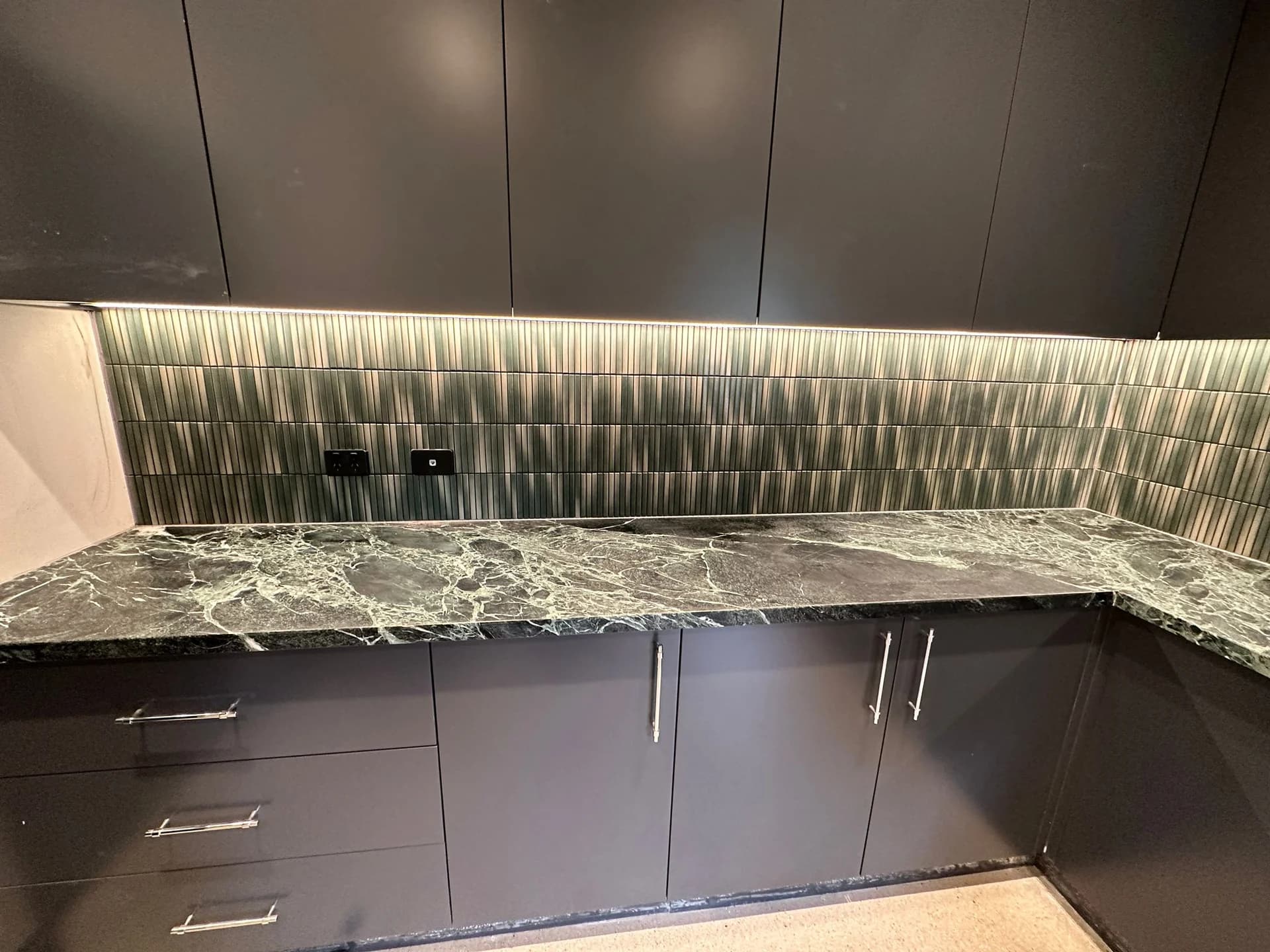Green vertical tiles behind a kitchen benchtop