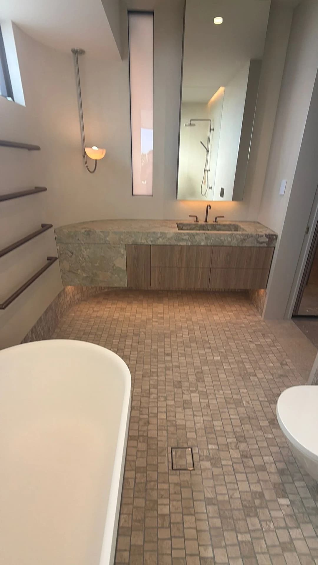 Small mosaic floor tiles around a freestanding bath and vanity