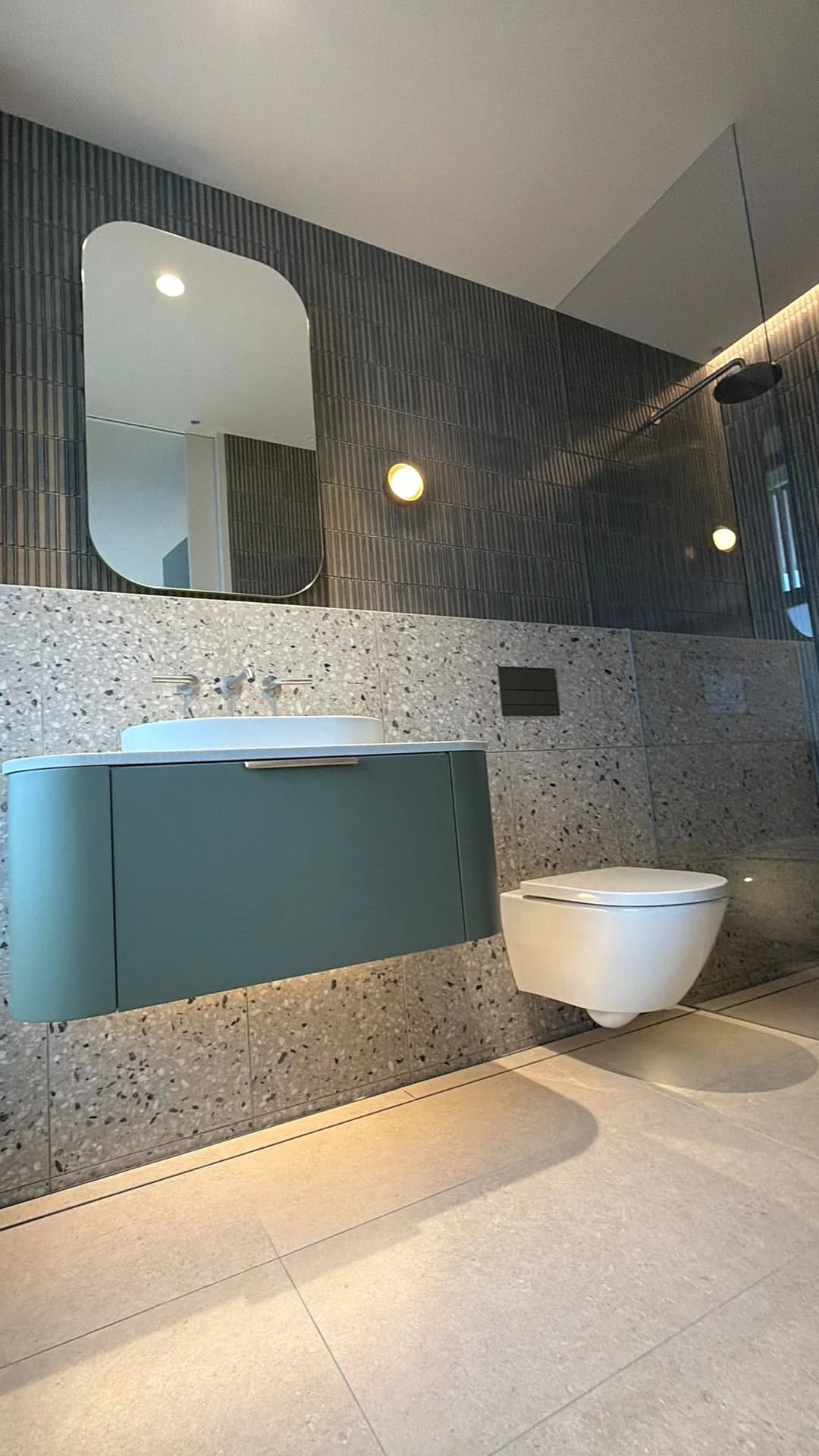 Vertical feature tiles and speckled wall tiles behind a green vanity