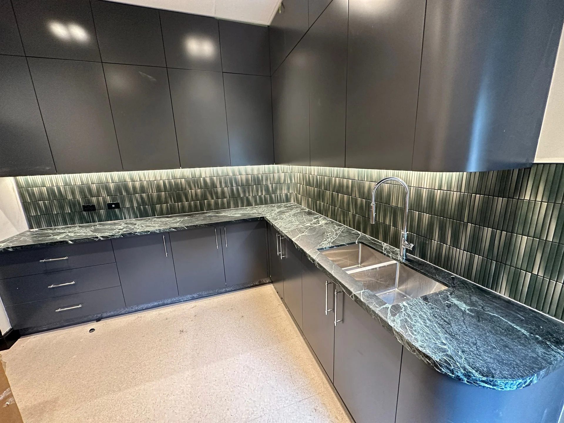 Green vertical splashback tiles around a kitchen corner
