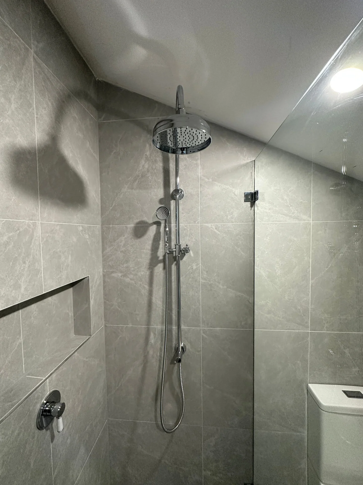 Grey tiled shower walls and patterned bathroom floor