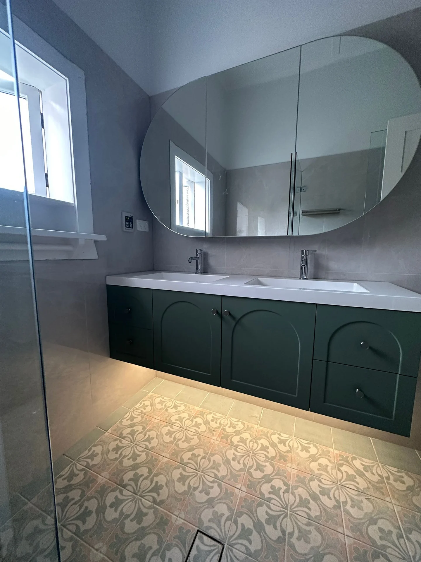 Patterned bathroom floor tiles beneath a green vanity