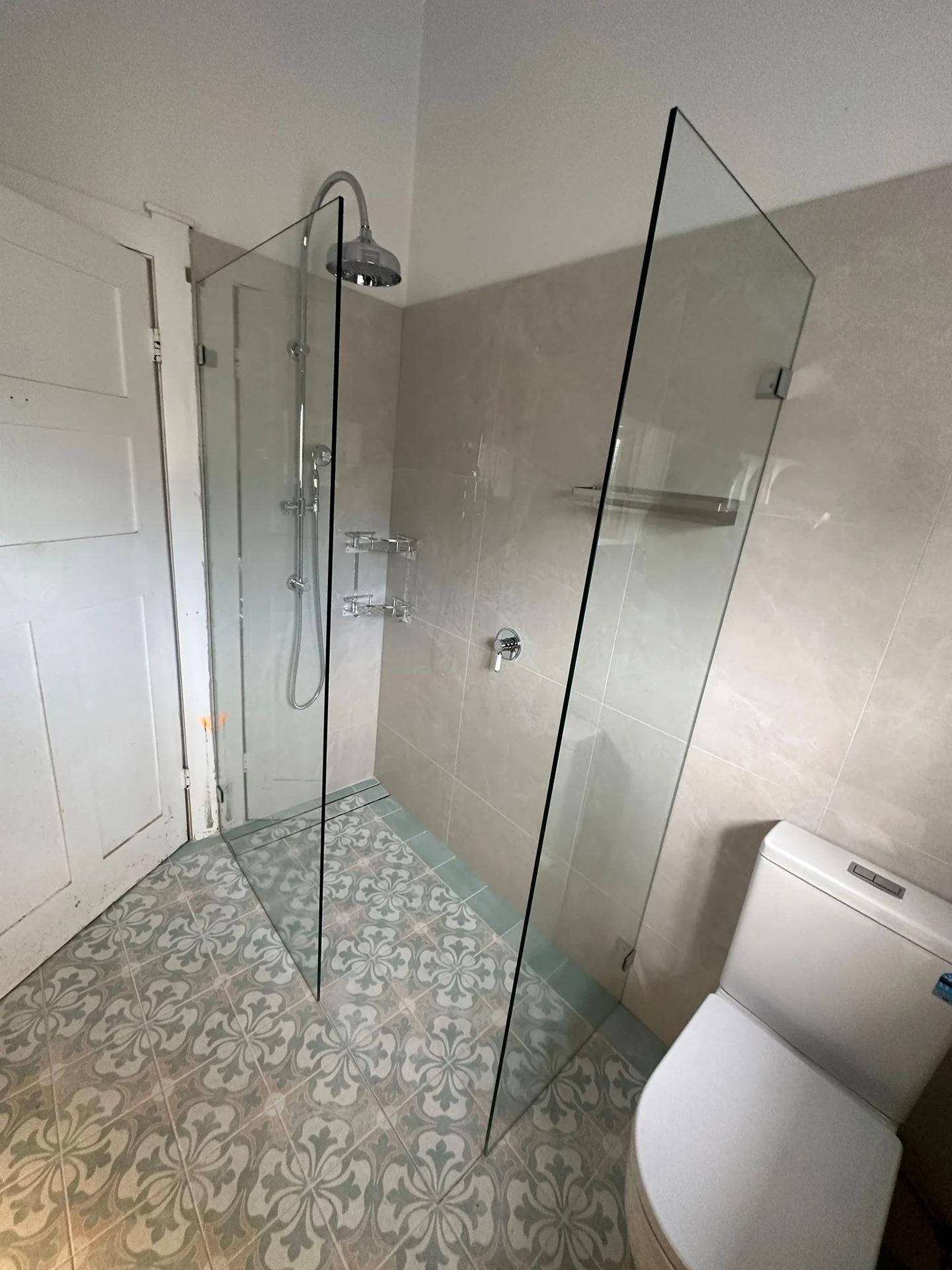 Patterned floor tiles beneath a glass shower enclosure