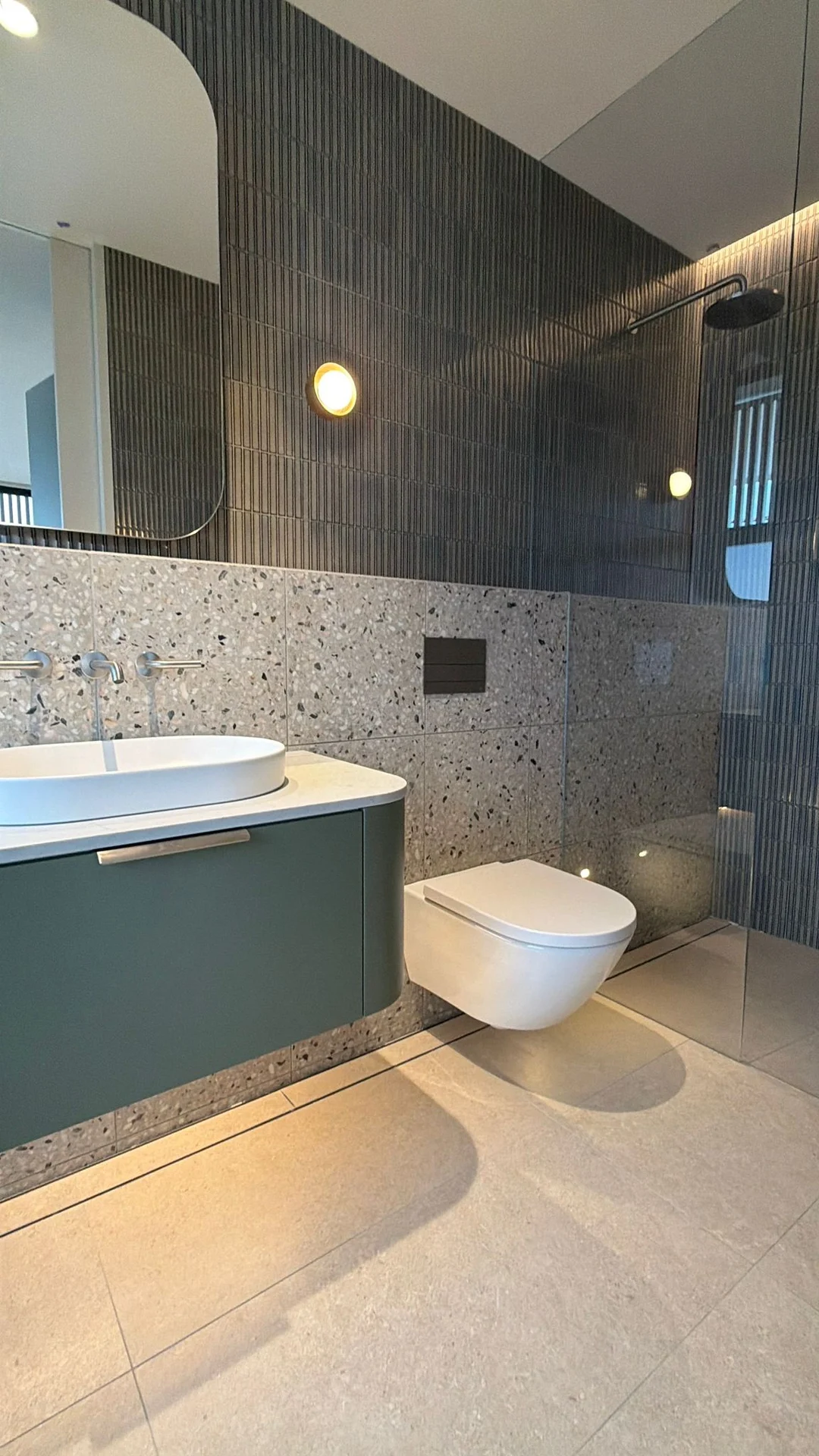 Bathroom feature tiling beside a bath and green vanity