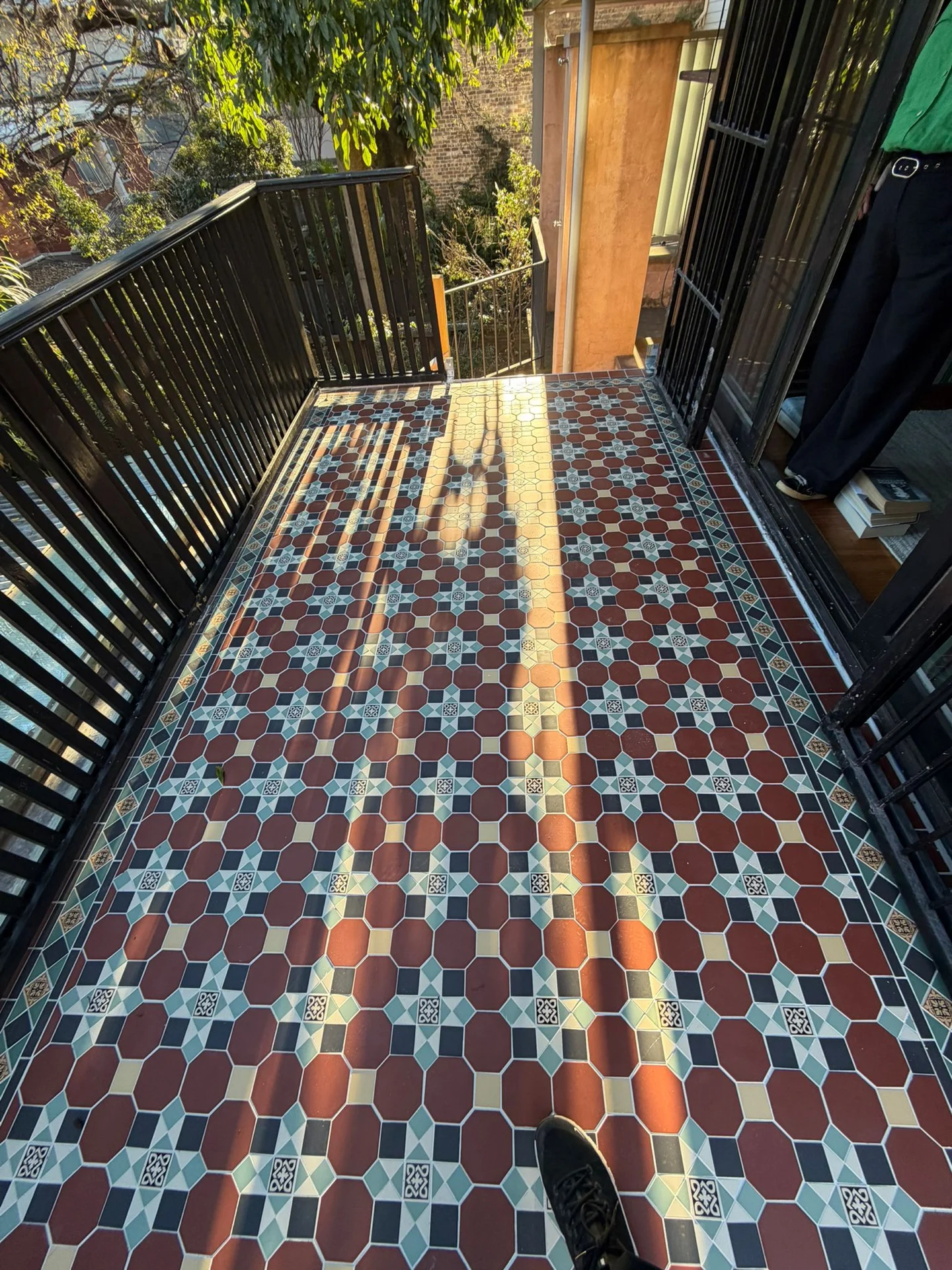 Patterned balcony floor tiles beside black railings