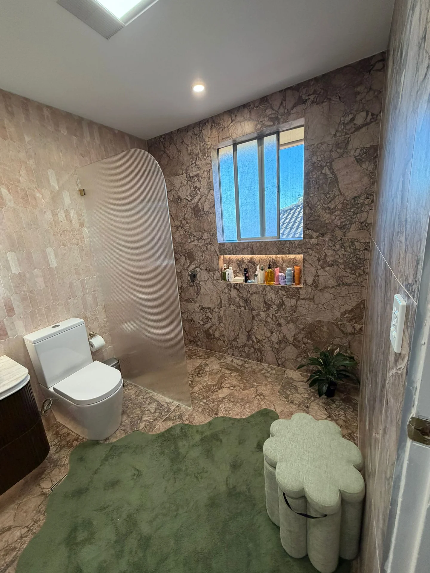 Pink stone-look bathroom wall tiles beside a window