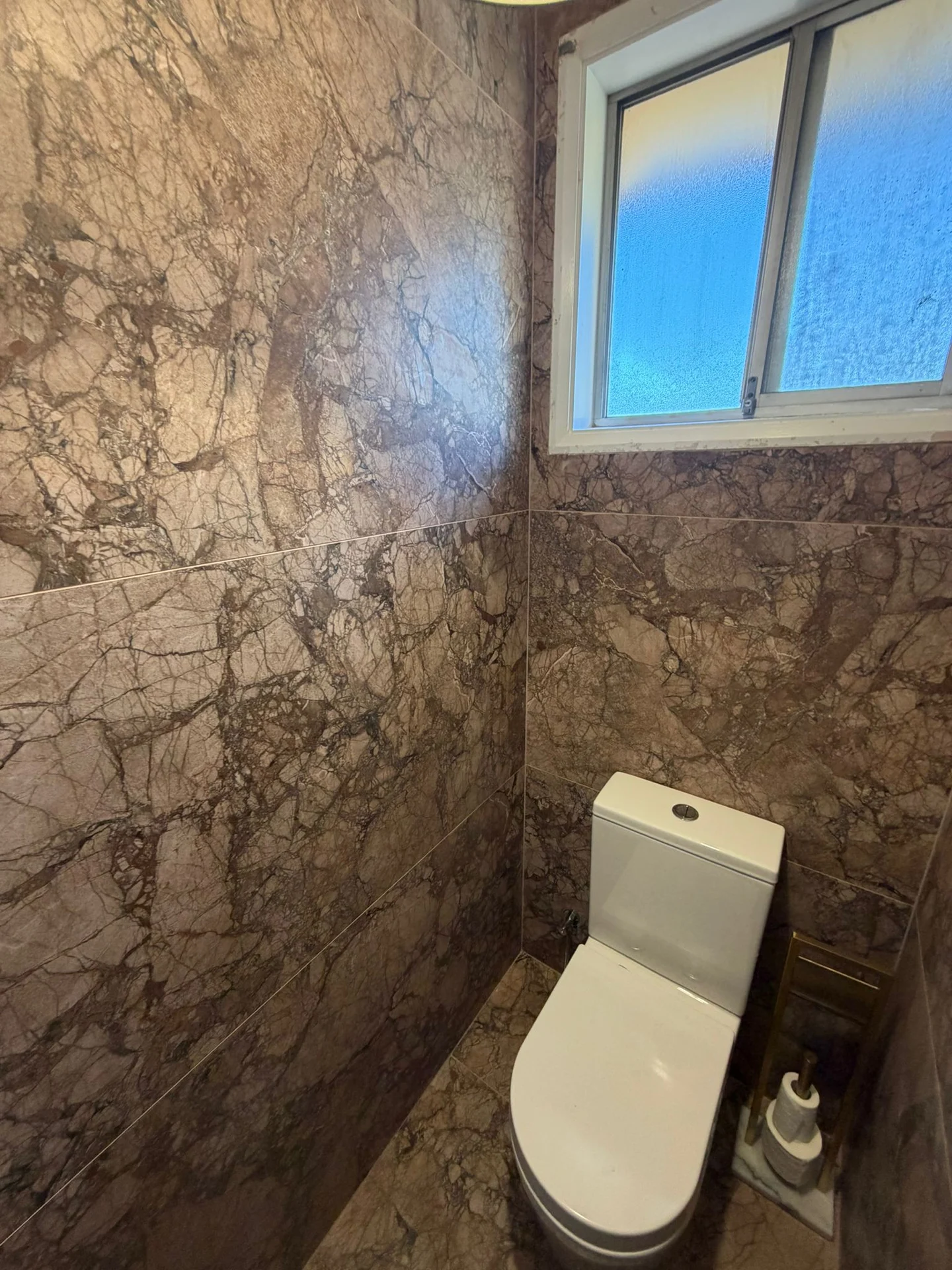 Pink stone-look wall tiles around a bathroom window